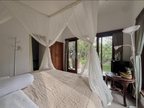 a bedroom with a white bed with a canopy at Gayatri in Ubud