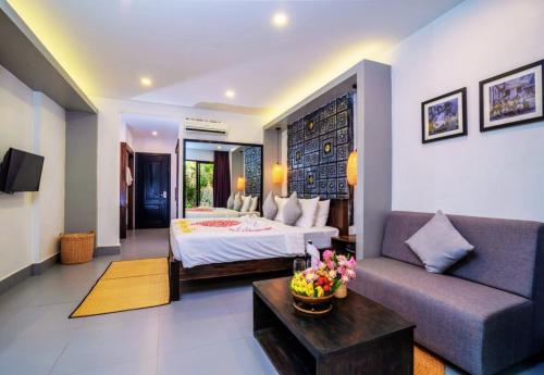 a hotel room with a bed and a couch at Angkor Home 27 in Phumĭ Réach Born