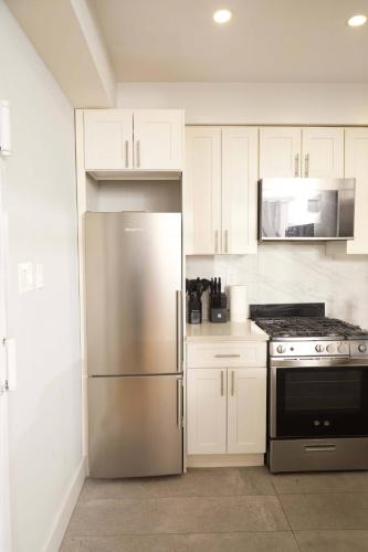 a kitchen with white cabinets and a stainless steel refrigerator at The Gray Loft Escape NYC Edition. in New York