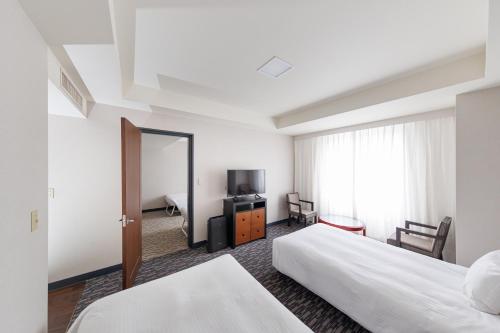 a hotel room with two beds and a mirror at Kokusai 21 International Hotel in Nagano