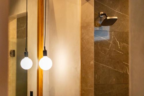 two lights hanging in a bathroom with a shower at Suwa Villa Arenal in Fortuna