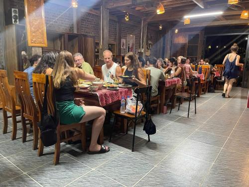 a group of people sitting at tables in a restaurant at Mai Chau Home Holiday in Mai Chau