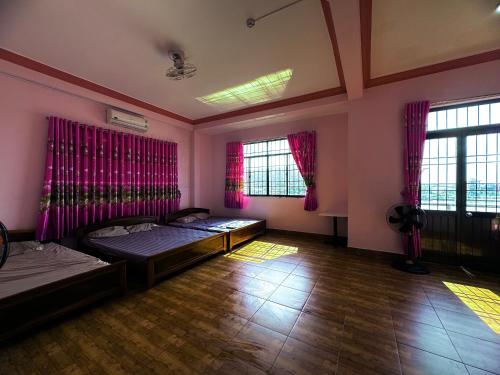 two beds in a room with pink walls and windows at Nhà Nghỉ M91 in Ha Tien