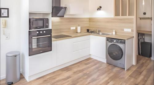 une cuisine avec des armoires blanches et une laveuse et une sécheuse dans l'établissement Le Repaire des Templiers 6 pers, à Troyes
