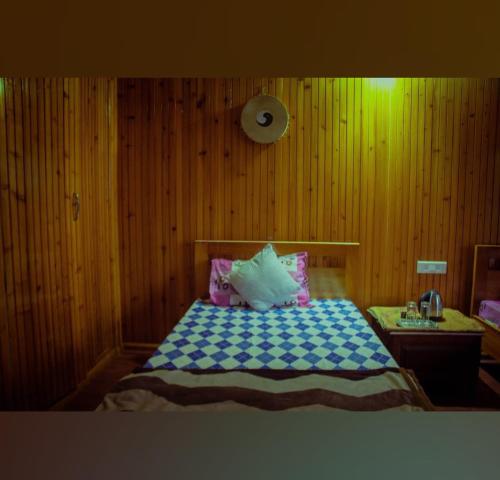 a bedroom with a bed and a wooden wall at Miryok Homes in Mirik