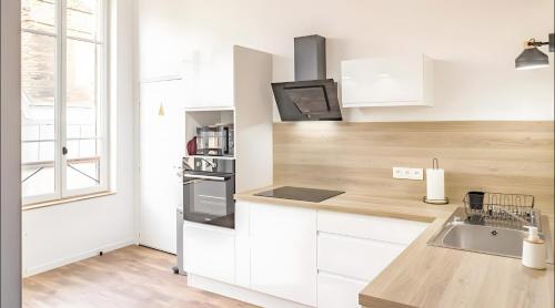 une cuisine avec des armoires blanches, un évier et une fenêtre dans l'établissement Le Repaire des Templiers 6 pers, à Troyes