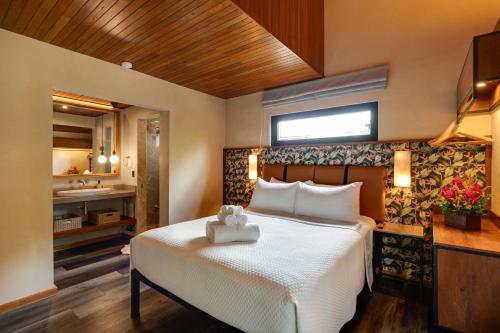 a bedroom with a white bed and a bathroom at Suwa Villa Arenal in Fortuna
