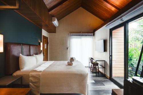 a bedroom with a bed with a teddy bear sitting on it at Suwa Villa Arenal in Fortuna