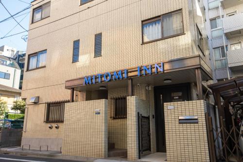 a brown brick building with a blue sign on it at Mitomi inn 京急蒲田駅 in Tokyo