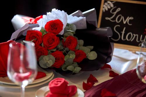 a bouquet of red roses on a table with a wine glass at PANAMA Nha Trang Hotel in Nha Trang