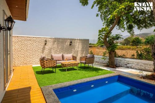 a backyard with a pool and two chairs and a table at StayVista at The Five Oaks - Private Pool Cottages in Karjat