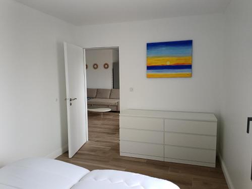 une chambre blanche avec un lit et un tableau au mur dans l'établissement Maison neuve en centre-ville, à Saint-Hilaire-de-Riez