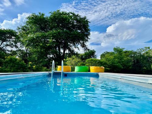 a swimming pool with blue water and yellow chairs at Mahoora Yala - by Eco Team in Yala