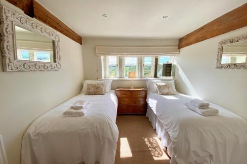 zwei Betten in einem Zimmer mit weißen Laken in der Unterkunft Woodlea Cottage in Huddersfield