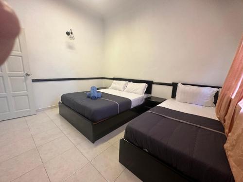 a room with two beds and a blue towel on the bed at 66 Semi-D Homestay in Teluk Intan