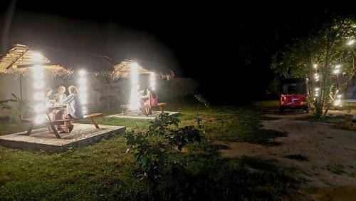 a group of people sitting on a picnic table at night at The Dream Inn Guesthouse Passikudah in Batticaloa