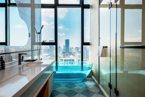 a bathroom with a tub with a view of the city at Oakwood BLEXUS Apartment Sanya in Sanya