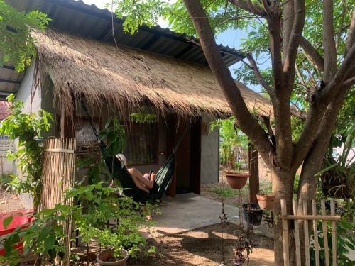 a woman chilling in a hammock outside a thatch hut at บ้านใจแปงโฮมสเตย์ Ban Jaipang Homestay in Pai