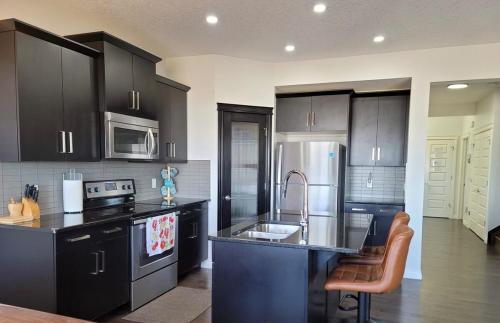 a kitchen with black cabinets and stainless steel appliances at Exquisite Entire 4- Bed rooms vacation home! in Calgary