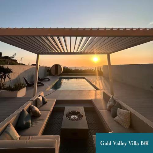 a patio with a couch and a pool with the sunset at Gold Valley Villa B in Futtsu