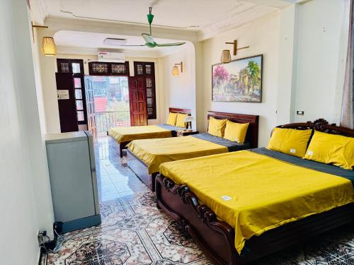 a room with three beds with yellow sheets at IL Divo Hostel & Spa Hàng Đào in Hanoi