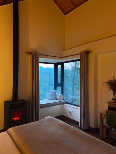 a bedroom with a bed and a window with a fireplace at Jaadooghar The Chitai Life in Almora