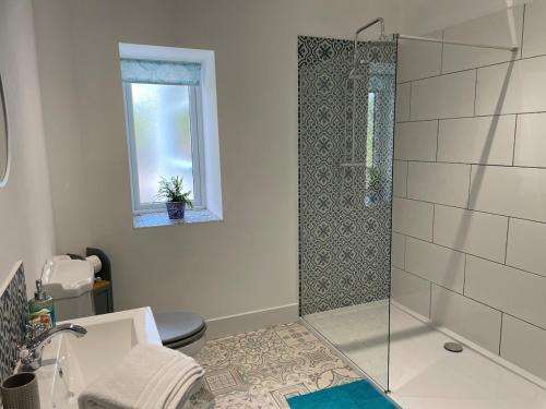 une salle de bain avec douche et toilettes et une fenêtre dans l'établissement Glencairn Cottage, à Moffat