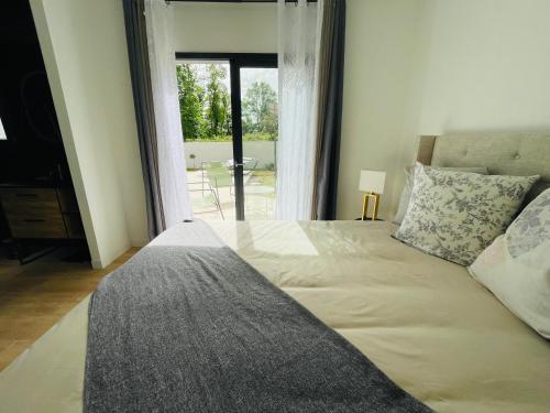 a bedroom with a large bed with a view of a patio at Maison moderne avec Piscine in Creysse