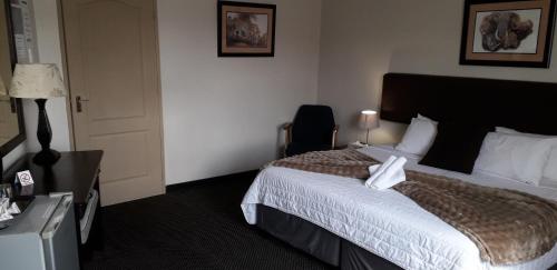 a hotel room with a bed and a chair at Kalahari Lodge Kimberley in Kimberley