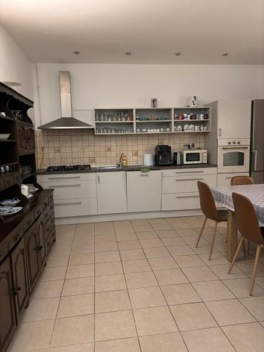 a kitchen with white cabinets and a table with chairs at The Blue in Csátalja