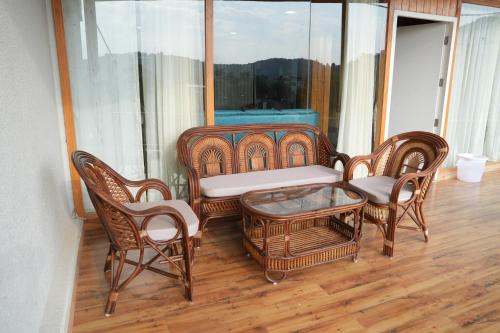 a group of wicker chairs and a bench on a balcony at Mountain BNB Hartola in Rāmgarh