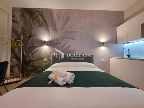 a bedroom with a large white bed with a kitchen at DEALCASA Guest House in Nuoro