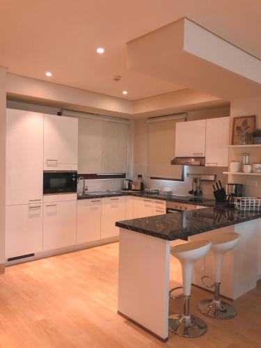 a kitchen with white cabinets and a large island with bar stools at Garden Villa in Ţāqah