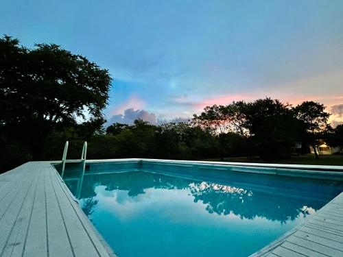 a blue swimming pool with a sunset in the background at Funky Leopard Safari Lodge Bordering Yala National Park in Kataragama
