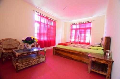 a bedroom with a bed and two windows and a table at Spitihome homestay in Kaja