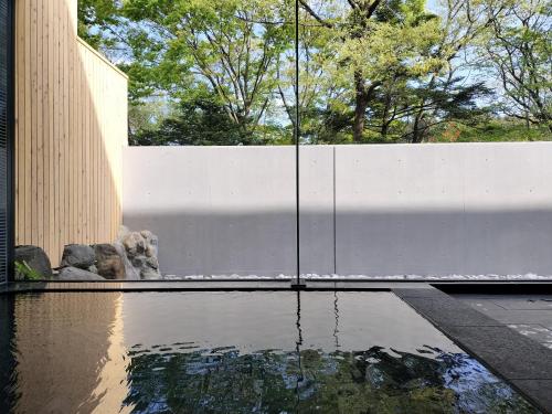 a pool of water next to a white fence at LEU Guest House in Nasushiobara