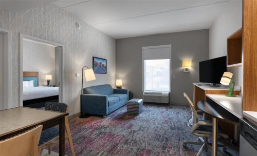 a hotel room with a bed and a blue couch at Home2 Suites by Hilton Greenville Airport in Greenville