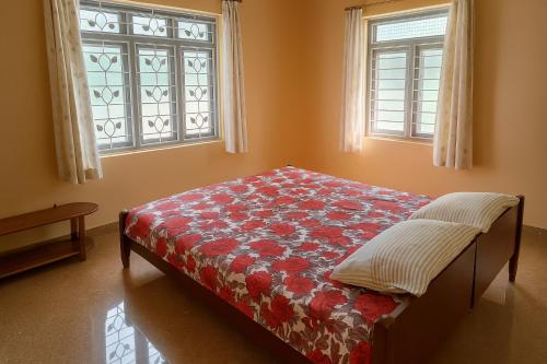 a bed in a room with two windows at Malnad Bliss in Sringeri