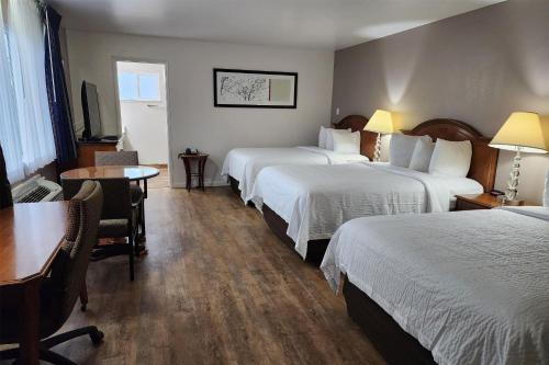 a hotel room with three beds and a table and a desk at Ramada Bayside Inn & Suites Eureka in Eureka