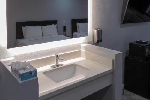 アナハイムにあるCapri Suites Anaheimのバスルーム(シンク、鏡にベッド1台付)