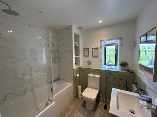 a bathroom with a toilet and a shower and a sink at The Barn Cottage in Oakworth
