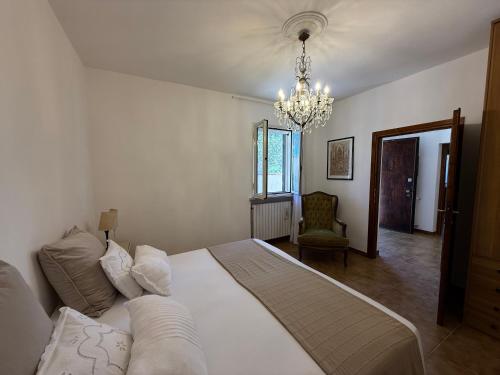 a bedroom with a large white bed and a chandelier at La Serenella in Porto Ercole