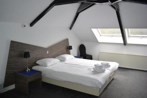 een slaapkamer met een groot bed met witte lakens en kussens bij Hotel Oranjeoord in Apeldoorn