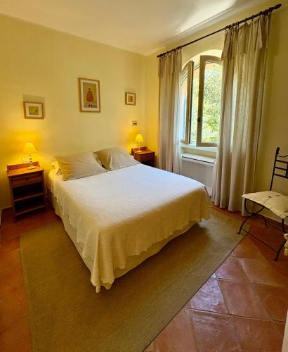 a bedroom with a white bed and a window at Le Mazet des Mûres in Grimaud