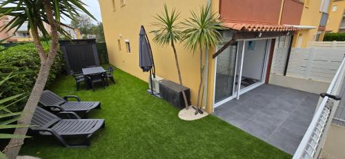 Elle offre une vue sur la terrasse dotée de chaises et d'un parasol. dans l'établissement Appartement agde - terrasses de la plage, au Cap d'Agde