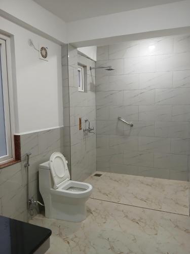 a white bathroom with a toilet and a shower at The Sherpas Rest in Darjeeling