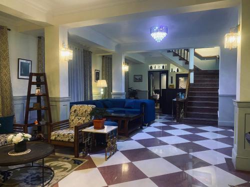 a living room with a blue couch and a checkered floor at The Sherpas Rest in Darjeeling