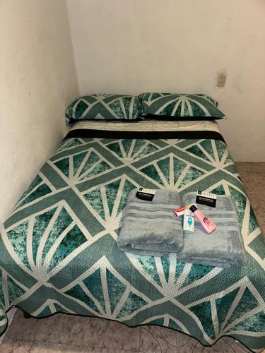 a bed with a green and white comforter at Casa Amplia Morelos in Ticumán
