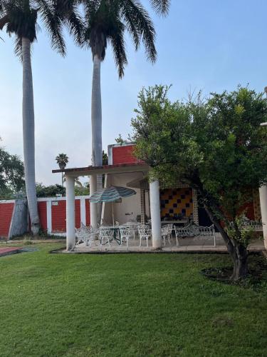 a building with tables and chairs and palm trees at Casa Amplia Morelos in Ticumán