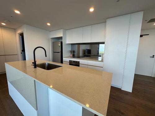 a kitchen with white cabinets and a sink at Cityscape Serenity at Southport in Gold Coast